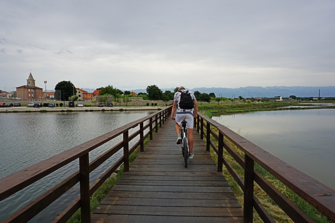 a man cycling across a wooden bridge