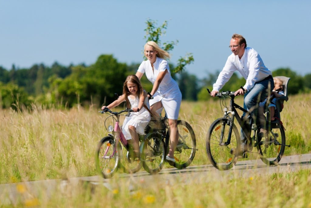 a man caring a baby in child seat on the bicycle, a woman and a girl riding bikes